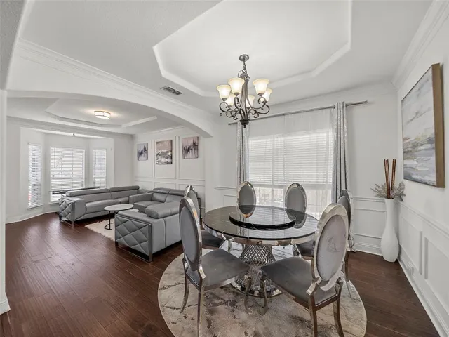 a dining room with furniture a chandelier and wooden floor