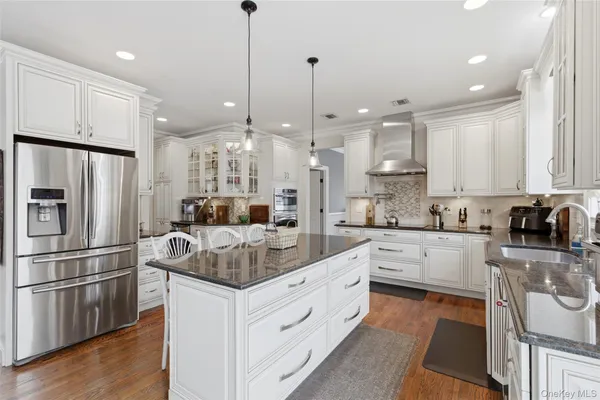 a large kitchen with stainless steel appliances kitchen island granite countertop a refrigerator a oven and a sink with granite countertops