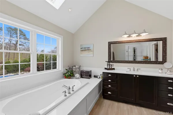 a bathroom with a bathtub a double vanity sink and mirror with bathtub