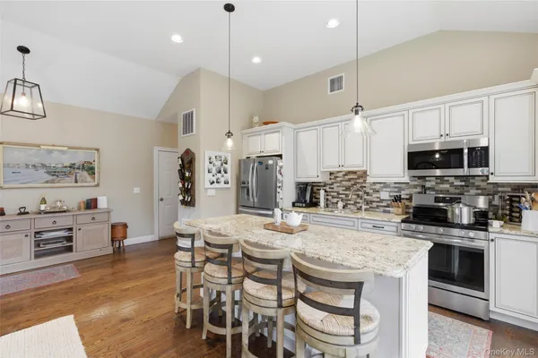 a kitchen with stainless steel appliances kitchen island granite countertop a kitchen island hardwood floor and a sink
