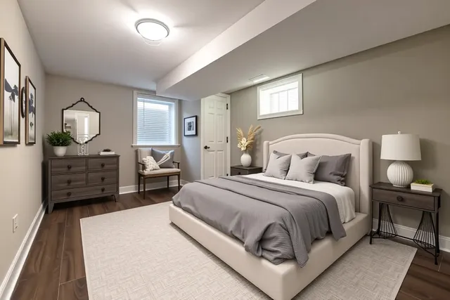 a spacious bedroom with a bed a mirror on dresser and a chandelier