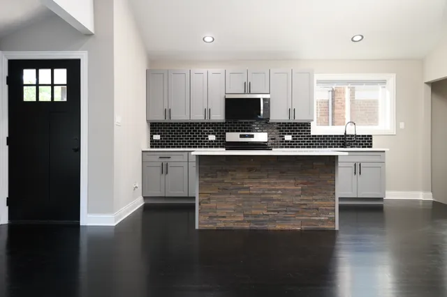 a kitchen with kitchen island a sink appliances cabinets and a counter top space