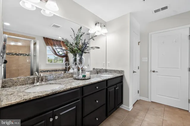 a bathroom with a granite countertop double vanity and a mirror