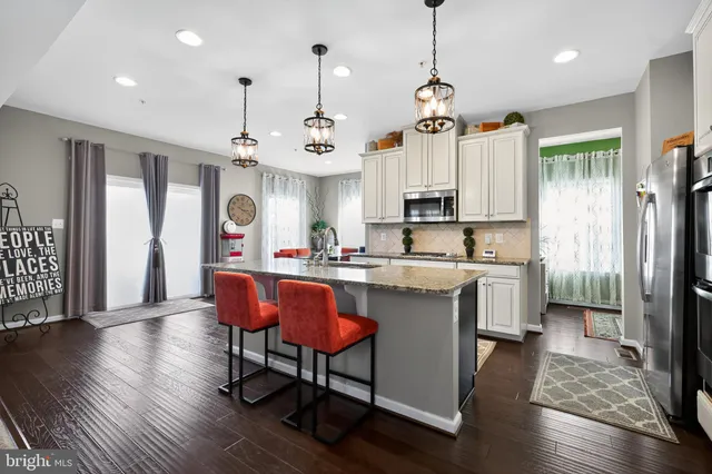 a kitchen with stainless steel appliances granite countertop a refrigerator a sink dishwasher a stove and white cabinets with wooden floor