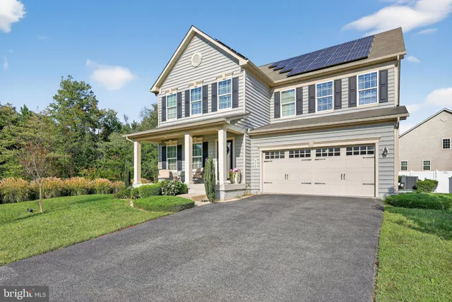 a view of a white house with a big yard and potted plants and large trees