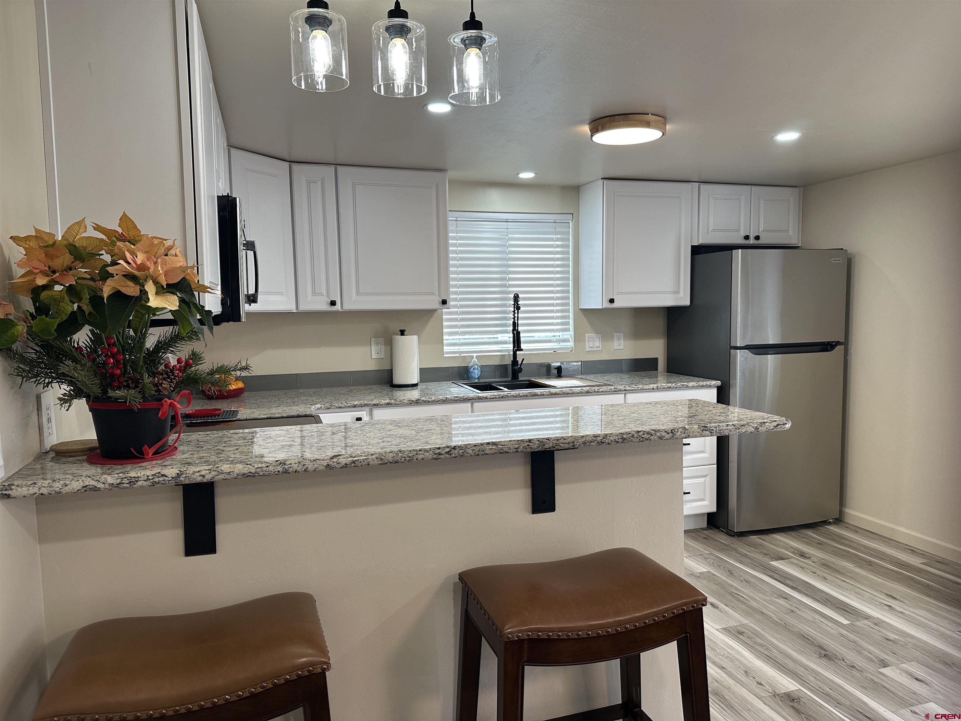 40 Hidden Lane Durango, CO 81303 - Photo 17 of 38 a kitchen with stainless steel appliances granite countertop a sink dishwasher a refrigerator a stove and a dining table with wooden floor