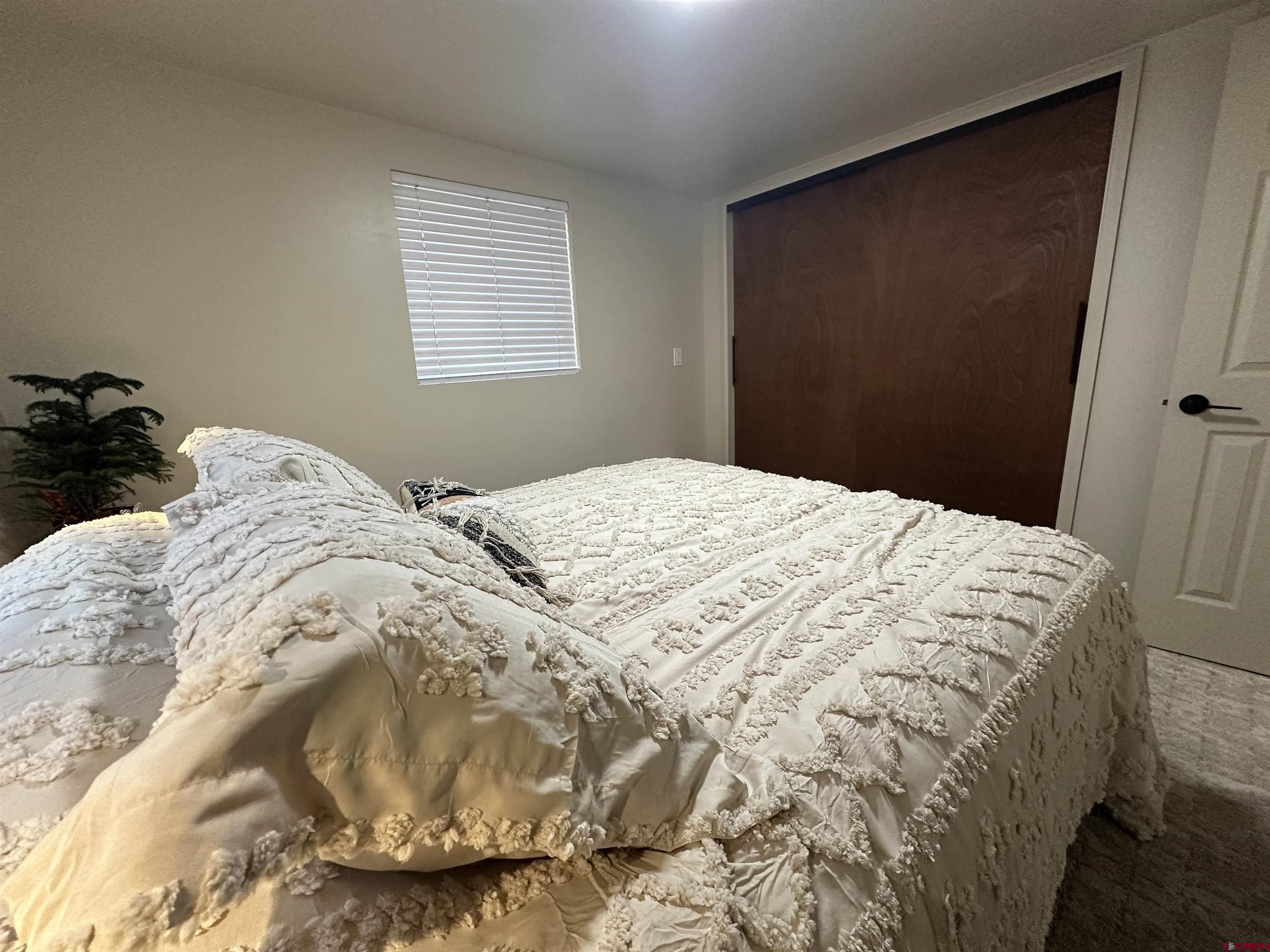 40 Hidden Lane Durango, CO 81303 - Photo 23 of 38 a large bed sitting in a bedroom next to a window and a wooden chair