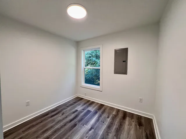 an empty room with wooden floor and windows