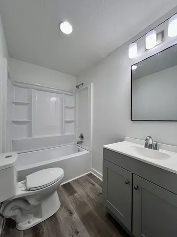 a bathroom with a bathtub shower sink vanity mirror and toilet