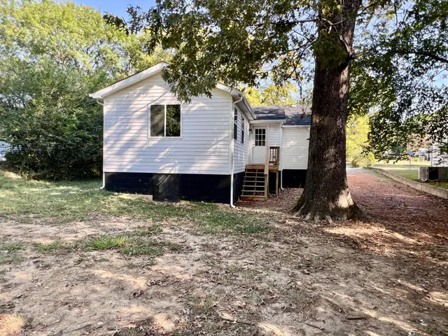 a view of a house with backyard and trees