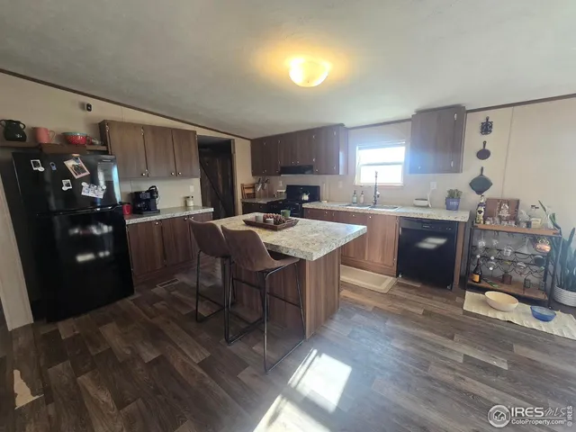 a kitchen with stainless steel appliances granite countertop a sink dishwasher a stove a refrigerator and a dining table with wooden floor