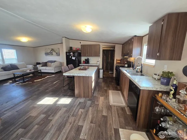 a large kitchen with stainless steel appliances a stove a sink dishwasher a dining table and chairs with wooden floor