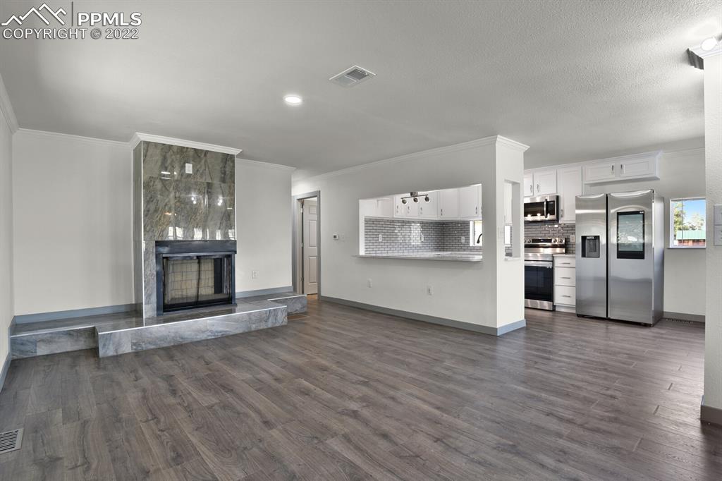 24365 Elbert Road Elbert, CO 80106 - Photo 4 of 19 an empty room with wooden floor and kitchen view