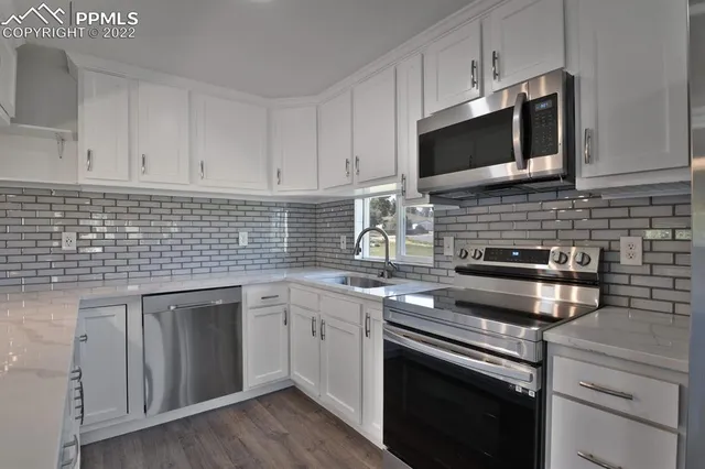 a kitchen with stainless steel appliances granite countertop a sink stove and microwave