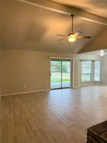 an empty room with wooden floor chandelier and windows
