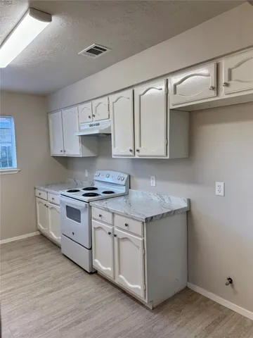 a kitchen with stainless steel appliances granite countertop a stove and a white cabinets