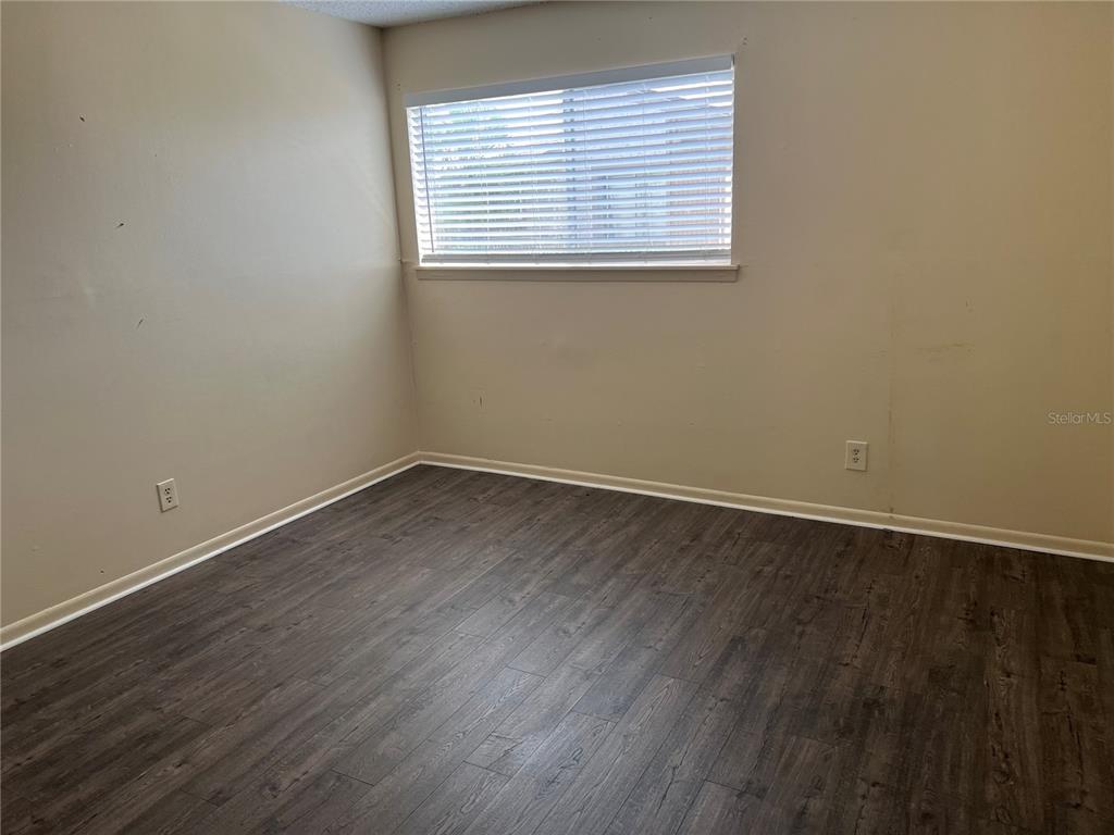 6312 Newtown Circle, Unit 12B3 Tampa, FL 33615 - Photo 7 of 10 an empty room with wooden floor and a window