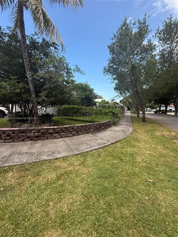 a view of a backyard with couches plants and large trees
