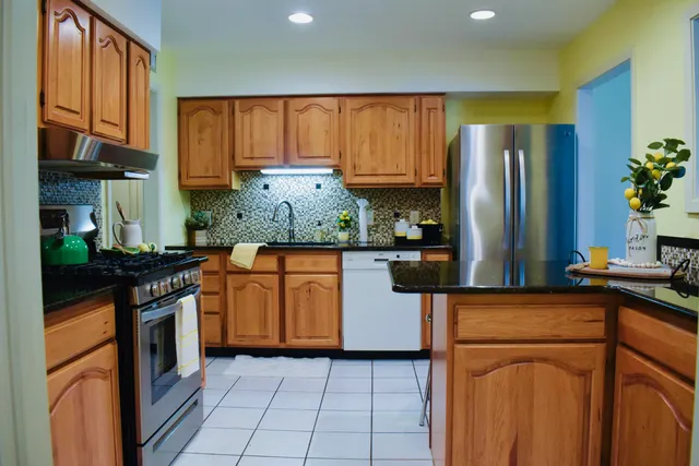 a kitchen with stainless steel appliances granite countertop a refrigerator a stove top oven and a sink