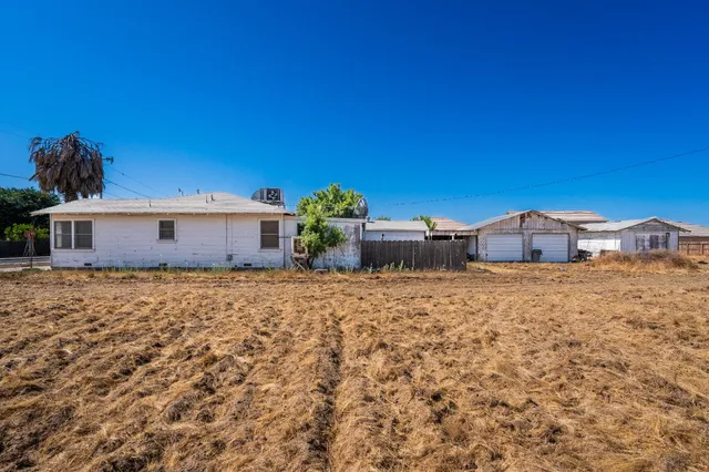 an empty room with chandelier fan and windows