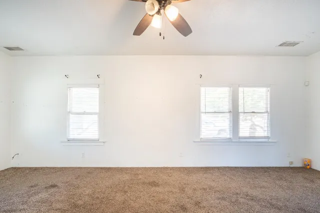 en empty room with windows and ceiling fan