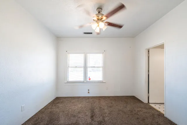 an empty room with windows and fan