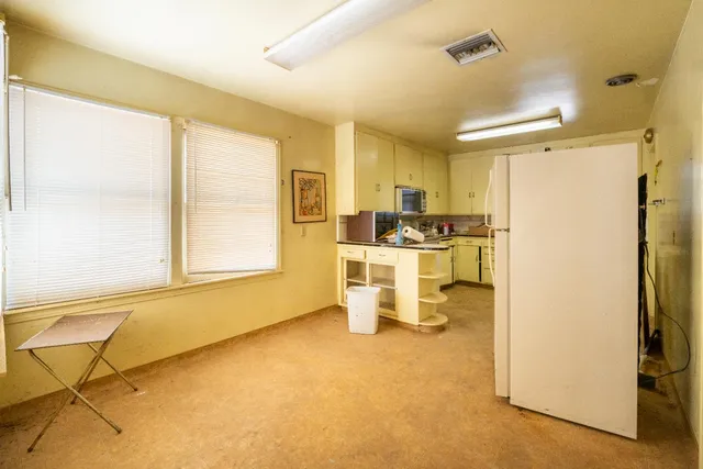 a kitchen with stainless steel appliances granite countertop a refrigerator a sink dishwasher and wooden cabinets with wooden floor