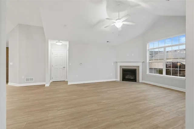 an empty room with wooden floor fireplace and windows