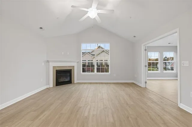 an empty room with wooden floor fireplace and windows