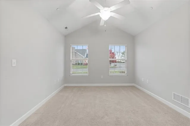 an empty room with windows and fan
