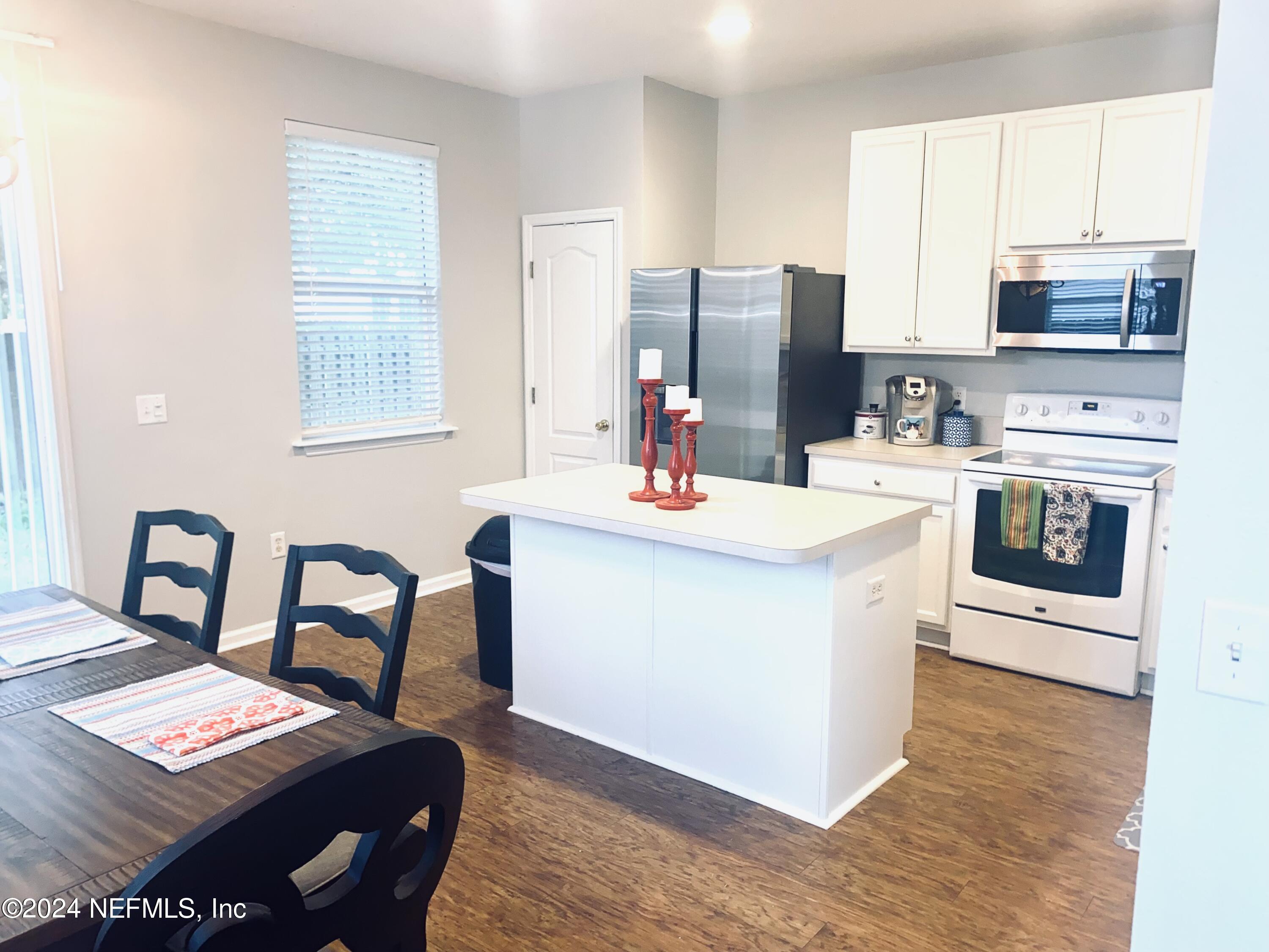 1108 Nochaway Drive St. Augustine, FL 32092 - Photo 5 of 11 a kitchen with stainless steel appliances kitchen island granite countertop a table chairs and a refrigerator