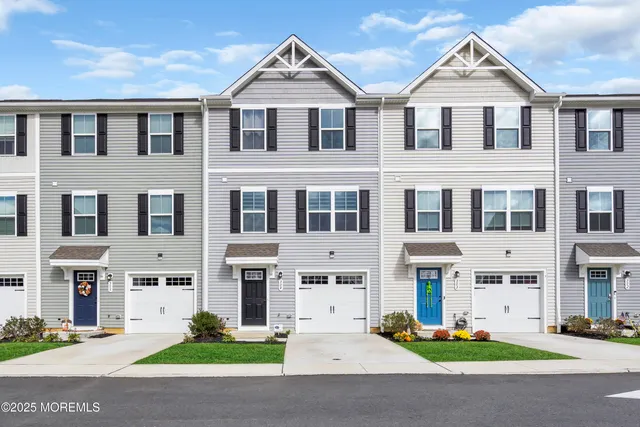 a view of a white house with large windows and a table and chairs in a yard