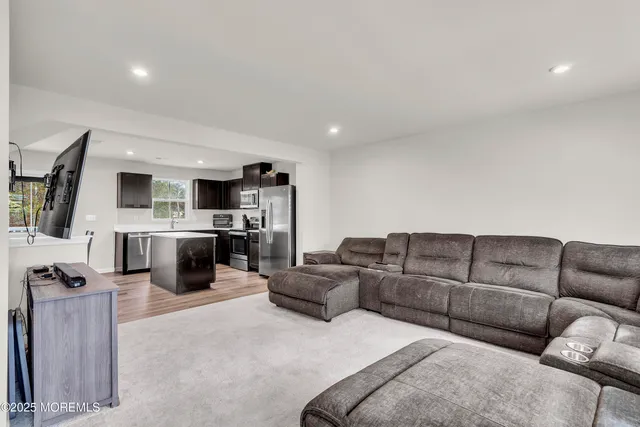 a living room with furniture white kitchen view and a couch