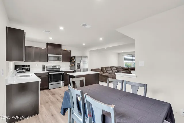 a kitchen with stainless steel appliances kitchen island granite countertop a sink dishwasher a stove a kitchen island with chairs and wooden floor