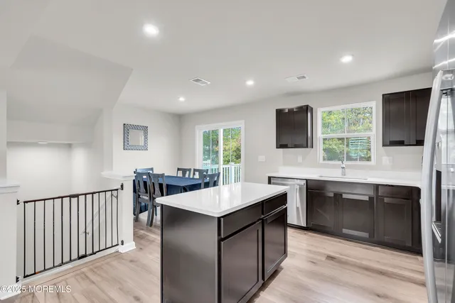 a large kitchen with granite countertop a sink and dishwasher a stove top oven with wooden floor