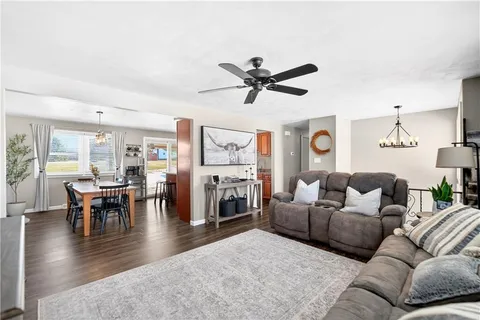 a living room with furniture a fireplace and a dining table with wooden floor