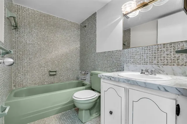 a bathroom with a granite countertop toilet a sink a mirror and bathtub