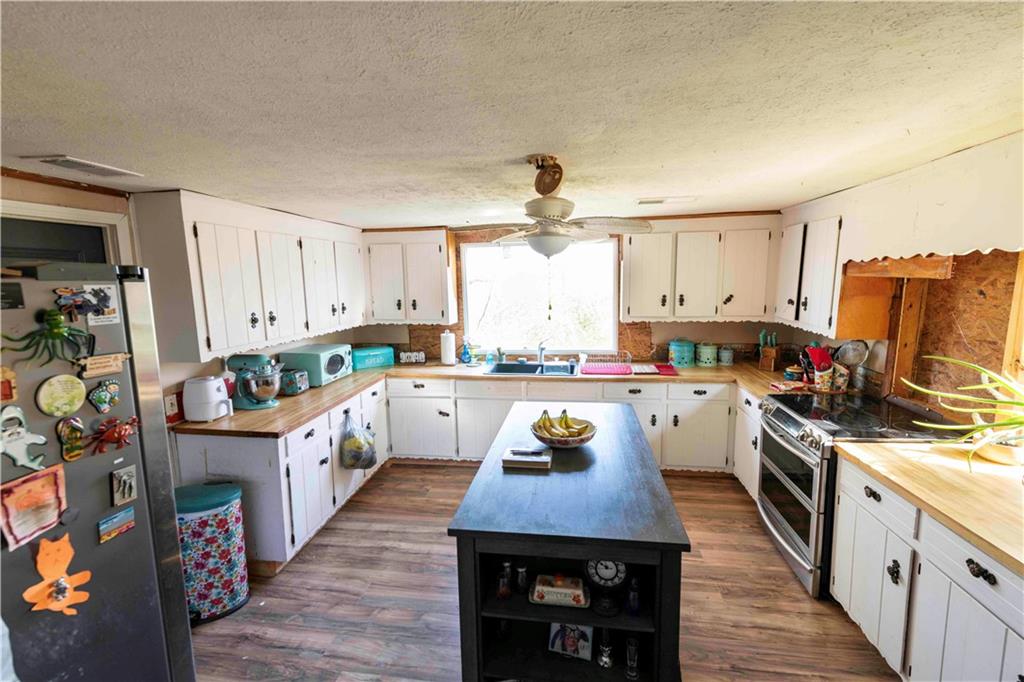 946 Hightower Loop Road Ranger, GA 30734 - Photo 12 of 22 a kitchen with stainless steel appliances a stove a sink dishwasher a refrigerator white cabinets and wooden floor