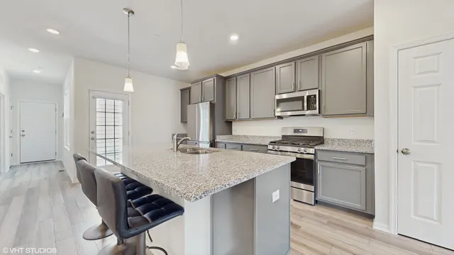 a kitchen with kitchen island a stove a sink and a refrigerator with wooden floor