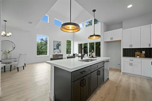a kitchen with stainless steel appliances a stove a sink dishwasher and a dining table with wooden floor