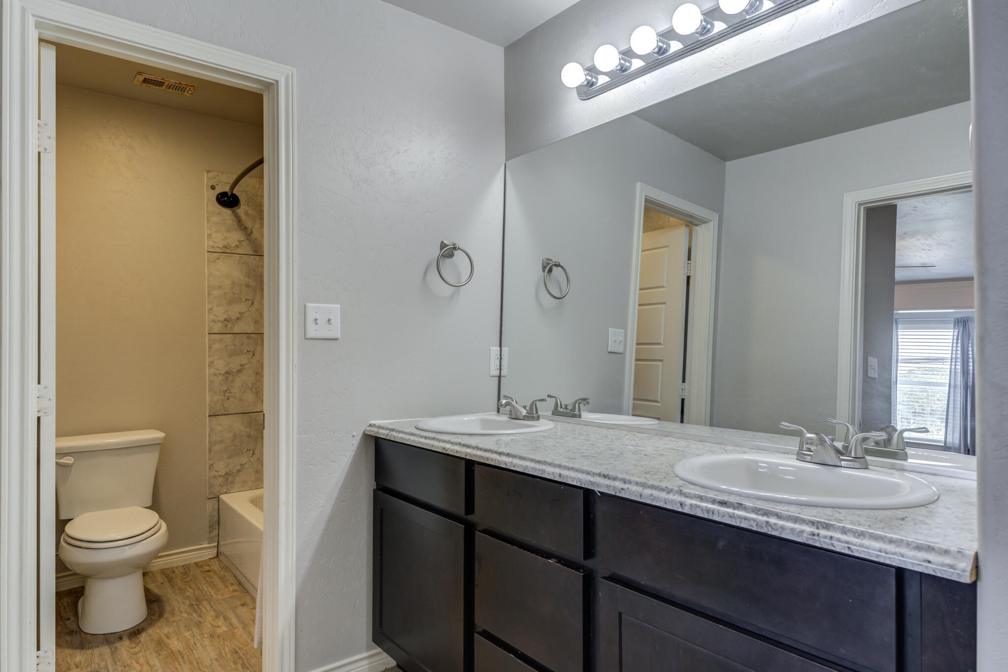 4320 52nd Street Lubbock, TX 79413 - Photo 27 of 59 a bathroom with a granite countertop sink toilet a large mirror and shower