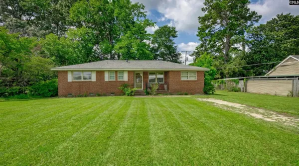 a view of a house with a yard plants and large tree