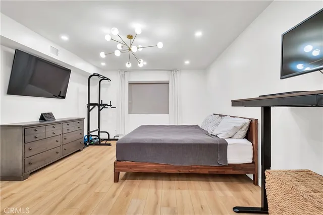 a bedroom with a bed a flat screen tv and a chandelier