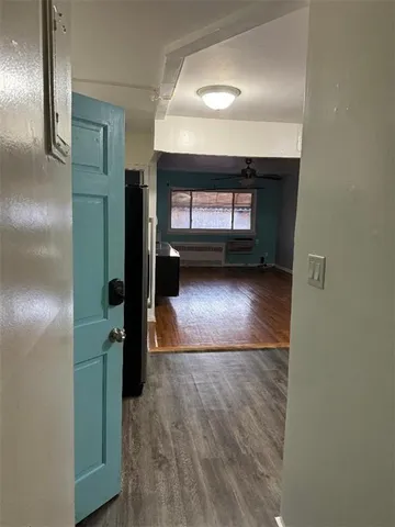 a view of a hallway with wooden floor and a kitchen