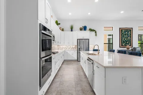 a large white kitchen with stainless steel appliances