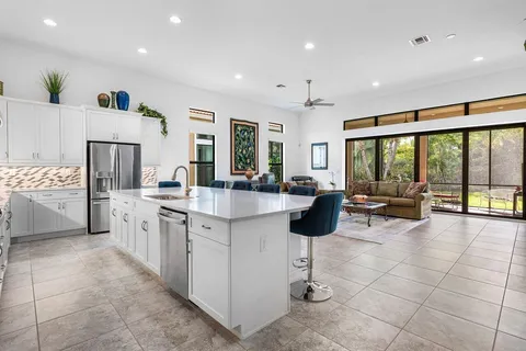 a large kitchen with stainless steel appliances a large counter top a stove and a large window