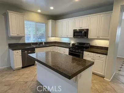 a kitchen with kitchen island granite countertop a sink a stove oven a counter top space and cabinets