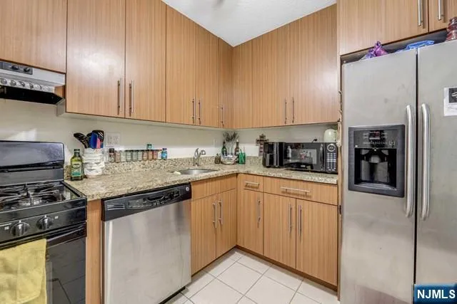 a kitchen with stainless steel appliances granite countertop a stove a sink and a refrigerator