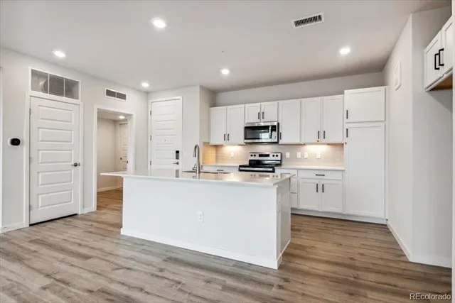 a kitchen with kitchen island a sink a center island stainless steel appliances and cabinets