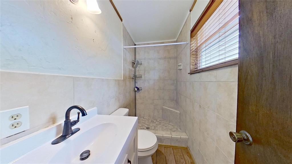 900 Silver Creek Azle Road Azle, TX 76020 - Photo 12 of 27 Bathroom with a white vanity and integrated sink, a dark bronze faucet, and a tiled shower with a built-in bench